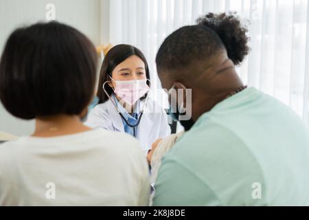 Donna asiatica medico pediatra tenere stetoscopio per l'esame una piccola ragazza paziente e heck cuore polmoni di bambino, buon medico di famiglia in visita bambino a casa Foto Stock