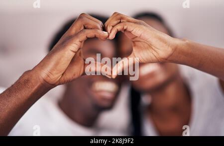 L'amore vive qui, una giovane coppia che forma un cuore unendosi le mani. Foto Stock