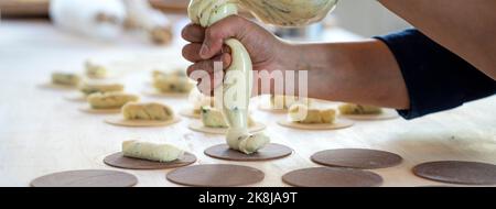 Banner orizzontale o testata con donna prepara ravioli freschi all'interno della fabbrica di pasta. Utilizzando una borsa di pasticceria o sac una poche per fare la pasta farcita raviol Foto Stock