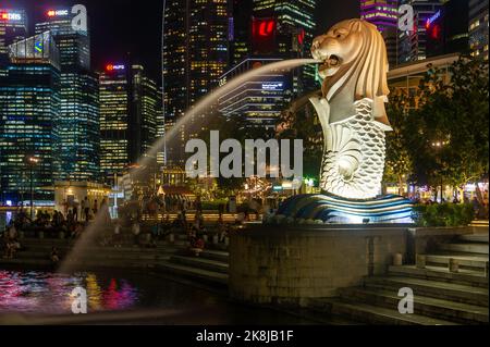 Il Merlion di Singapore e' stato preso di notte con il quartiere Centrale degli Affari sullo sfondo Foto Stock