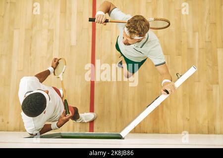 Hai incontrato la partita. Colpo ad angolo alto di due giovani uomini in un campo da squash. Foto Stock