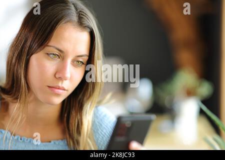 Giovane donna che usa uno smartphone seduto in un ristorante o a casa Foto Stock