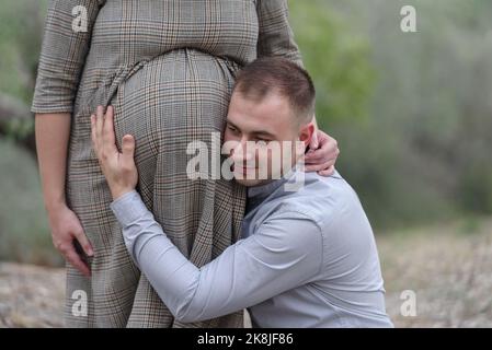 Padre sente il suo bambino nel ventre della donna in natura Foto Stock