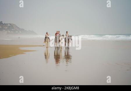 Un gruppo di cavalieri sulla spiaggia vicino a Tarifa, durante il tramonto, Zahara de los Atunes, Costa de la Luz, Andalusia, Spagna. Foto Stock