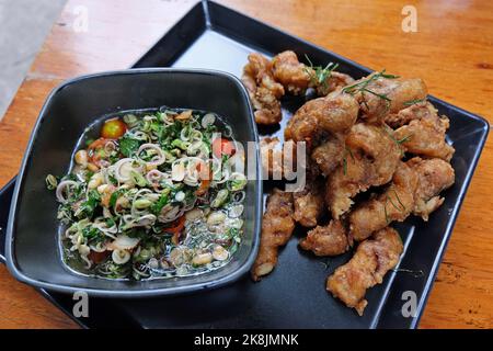 Primo piano di pesce fritto e in pastella con salsa alle erbe Foto Stock