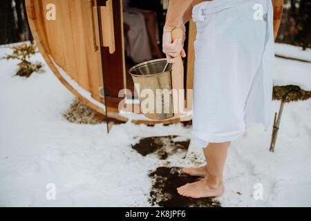 Vista dal basso angolo degli anziani che entrano nella vasca idromassaggio all'aperto con secchio. Foto Stock