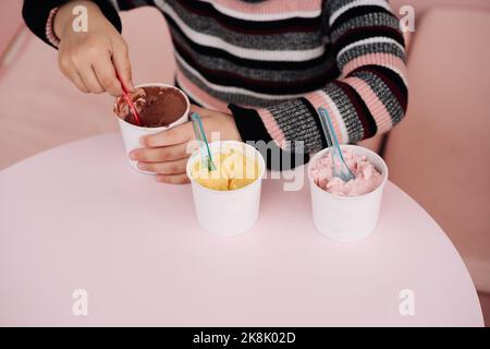 I bambini mangiano gelato in una caffetteria. Set di ciotole con vari gelati con sapori diversi e ingredienti freschi Foto Stock