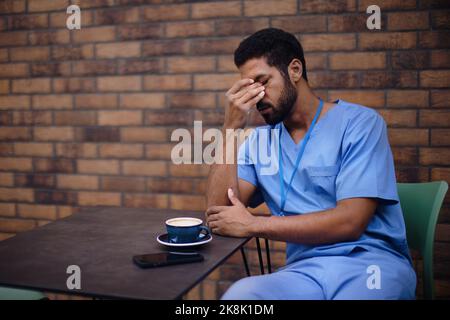 Uomo caregiver stanco che riposa all'aperto, di fronte a casa nutre. Foto Stock
