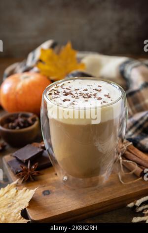 Caffè speziato latte di zucca, sciarpa calda e foglie di acero su sfondo rustico. Stagione autunnale con bevanda calda. Foto Stock