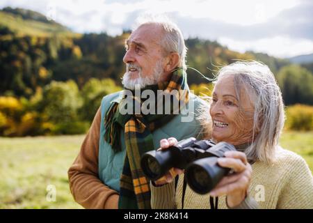 Coppia anziana che guarda la vista attraverso binocoli durante la passeggiata autunnale. Foto Stock