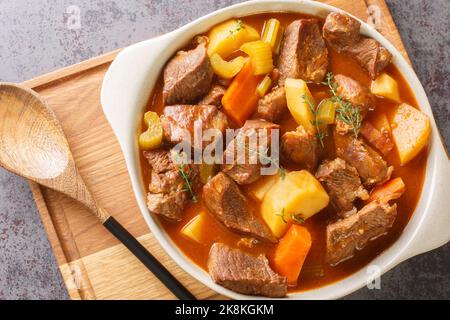 Stufato tradizionale irlandese di carne e verdure in una salsa spessa a base di birra scura primo piano in una pentola sul tavolo. Vista orizzontale dall'alto Foto Stock