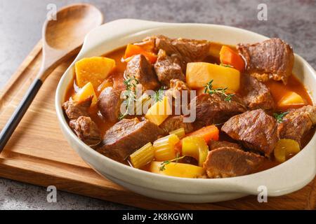 Stufato tradizionale irlandese di carne e verdure in una salsa spessa a base di birra scura primo piano in una pentola sul tavolo. Orizzontale Foto Stock