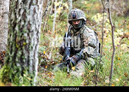 Ämari, Estonia. 24 ottobre 2022, Estonia, Ämari: Un soldato della Bundeswehr si accola in una zona boscosa durante un esercizio presso la base aerea di Ämari. Le forze aeree e gli ispettori della Marina visitano l'Estonia per la manovra della Tigre Baltica 2022, lunga quasi un mese. Le unità della Marina militare e dell'aeronautica in Estonia praticano la protezione delle infrastrutture critiche sul fianco orientale della NATO. Foto: Christophe Gateau/dpa Credit: dpa picture Alliance/Alamy Live News Foto Stock