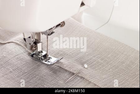 Primo piano di una moderna macchina da cucire, piedino premiatore e capo di abbigliamento da cucire ad aghi. Foto Stock