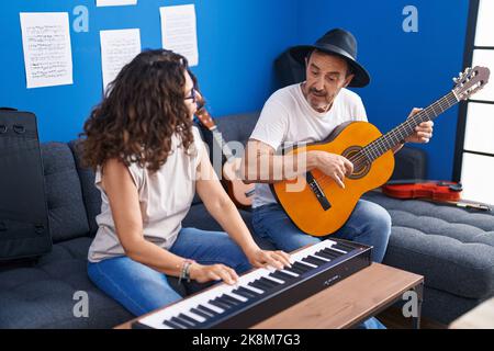 Musicisti uomo e donna che suonano pianoforte e chitarra classica in studio musicale Foto Stock