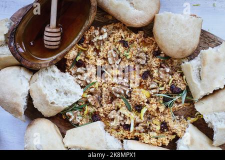 Giacitura piana di un pannello di burro con burro fresco aromatizzato alla zucca, mirtilli rossi secchi, scorza di limone, noci, foglie di rosmarino, e sgocciolato di miele Foto Stock