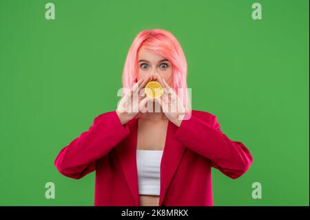 Femmina che ricopre la bocca con agrumi prima della fotocamera Foto Stock