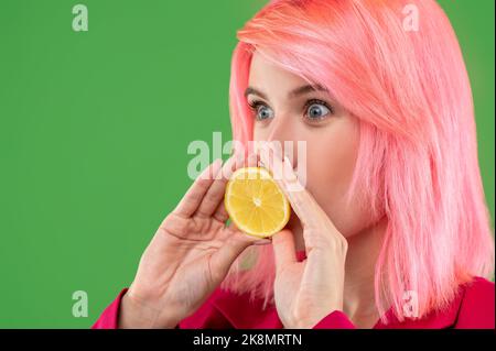 Donna maliziosa che posa agrumi gialli sullo sfondo verde Foto Stock