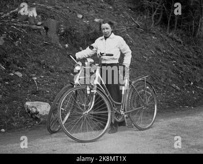 Norvegia, estate 1943 vita quotidiana durante la guerra. I permessi di viaggio erano difficili da raggiungere durante la seconda guerra mondiale, motivo per cui molti hanno scelto una bicicletta. Una giovane coppia ha affrontato il tratto Oslo / Ålesund. Donna in pantaloni lunghi e giacca bianca tiene entrambe le moto durante una sosta. Foto: NTB Foto Stock