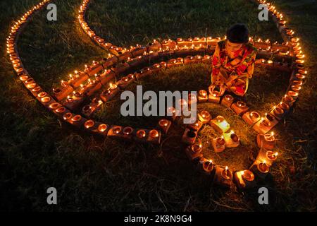 Narayanganj, Dhaka, Bangladesh. 24th Ott 2022. I devoti indù illuminano ''Diyas'' (lampade di terra) su un Rangoli, una cornice di motivi decorati, come parte dei festeggiamenti di Diwali in un tempio locale a Narayanganj, Bangladesh. Molte lampade o candele ad olio leggero per simboleggiare una vittoria della luce sulle tenebre, e fuochi d'artificio sono accesi come parte delle celebrazioni. Il festival si svolge ogni anno secondo il calendario lunare indù. Credit: ZUMA Press, Inc. Credit: ZUMA Press, Inc./Alamy Live News Foto Stock