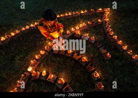 Narayanganj, Dhaka, Bangladesh. 24th Ott 2022. I devoti indù illuminano ''Diyas'' (lampade di terra) su un Rangoli, una cornice di motivi decorati, come parte dei festeggiamenti di Diwali in un tempio locale a Narayanganj, Bangladesh. Molte lampade o candele ad olio leggero per simboleggiare una vittoria della luce sulle tenebre, e fuochi d'artificio sono accesi come parte delle celebrazioni. Il festival si svolge ogni anno secondo il calendario lunare indù. Credit: ZUMA Press, Inc./Alamy Live News Foto Stock