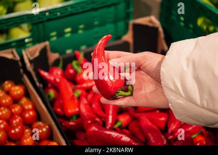 Una donna sceglie un pepe in un negozio di alimentari, primo piano. Foto Stock
