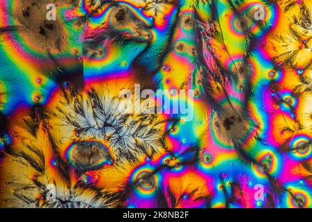 Macro fotografia estrema di cristalli di vitamina C che formano astratti modelli d'arte moderna, quando illuminati con luce polarizzata, sotto un microscopio Foto Stock