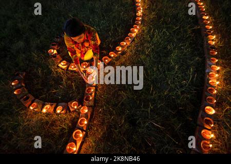 Narayanganj, Dhaka, Bangladesh. 24th Ott 2022. I devoti indù illuminano ''Diyas'' (lampade di terra) su un Rangoli, una cornice di motivi decorati, come parte dei festeggiamenti di Diwali in un tempio locale a Narayanganj, Bangladesh. Molte lampade o candele ad olio leggero per simboleggiare una vittoria della luce sulle tenebre, e fuochi d'artificio sono accesi come parte delle celebrazioni. Il festival si svolge ogni anno secondo il calendario lunare indù. Credit: ZUMA Press, Inc./Alamy Live News Foto Stock