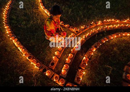 Narayanganj, Dhaka, Bangladesh. 24th Ott 2022. I devoti indù illuminano ''Diyas'' (lampade di terra) su un Rangoli, una cornice di motivi decorati, come parte dei festeggiamenti di Diwali in un tempio locale a Narayanganj, Bangladesh. Molte lampade o candele ad olio leggero per simboleggiare una vittoria della luce sulle tenebre, e fuochi d'artificio sono accesi come parte delle celebrazioni. Il festival si svolge ogni anno secondo il calendario lunare indù. Credit: ZUMA Press, Inc./Alamy Live News Foto Stock