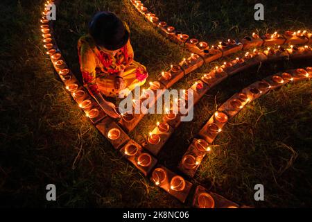 Narayanganj, Dhaka, Bangladesh. 24th Ott 2022. I devoti indù illuminano ''Diyas'' (lampade di terra) su un Rangoli, una cornice di motivi decorati, come parte dei festeggiamenti di Diwali in un tempio locale a Narayanganj, Bangladesh. Molte lampade o candele ad olio leggero per simboleggiare una vittoria della luce sulle tenebre, e fuochi d'artificio sono accesi come parte delle celebrazioni. Il festival si svolge ogni anno secondo il calendario lunare indù. Credit: ZUMA Press, Inc./Alamy Live News Foto Stock