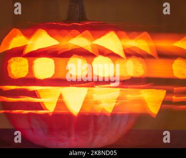 Un Jack-o'-lanterna con la faccia di un gatto si illumina di notte con la luce della candela. Foto Stock