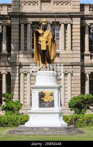 Un primo piano verticale della statua del re Kamehameha nel centro di Honolulu, con lo sfondo del palazzo Iolani Foto Stock