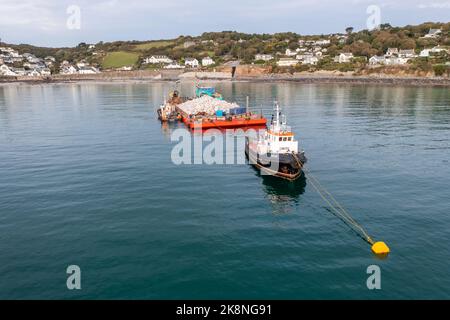 COVERACK, REGNO UNITO - 20 SETTEMBRE 2022. Un rimorchiatore nautico e una chiatta che consegnano pietra di corrido per consentire la riparazione delle difese marine a Coverack, Cornw Foto Stock