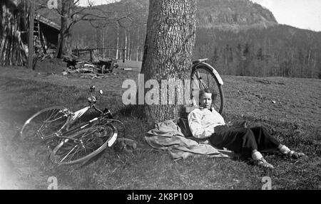 Norvegia, estate 1943 vita quotidiana durante la guerra. I permessi di viaggio erano difficili da raggiungere durante la seconda guerra mondiale, motivo per cui molti hanno scelto una bicicletta. Una giovane coppia ha affrontato il tratto Oslo / Ålesund. Donna in pantaloni lunghi e giacca bianca prende un respiro a terra lungo il percorso. Foto: NTB Foto Stock