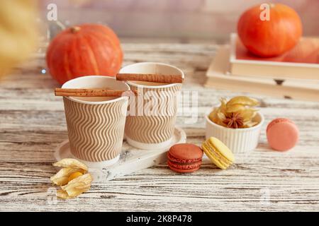 Estetica romantico pranzo autunnale - tazze di cartone con latte di zucca e bastoncini di cannella. Tempo di caffè stagionale con macaron. Accogliente atmosfera autunnale. Foto Stock