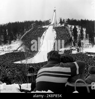 Oslo 19580316 Holmenkoll collina su Holmenkollagen. Migliaia di persone corrono il salto sotto la corsa di salto. In amore coppie in primo piano. Foto: NTB / NTB Foto Stock