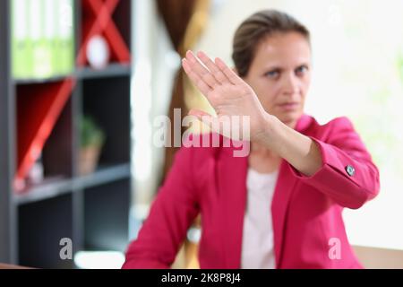 Donna seria che mostra un segno di stop, protestando contro la violenza domestica Foto Stock