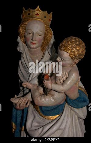 Il Cristo Bambino, con i capelli ricci dorati, si agginca una colomba come la Vergine Maria, indossando una corona gioiellata, lo tiene in braccio. Copia fedele della statua in legno di tiglio dei primi anni del 1400s, opera di uno scultore sconosciuto, nella chiesa cattolica romana di St. Nikolaus-Kirche a Kaub am Rhein, Rheinland-Pfalz, Germania. Foto Stock