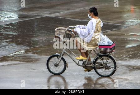 SAMUT PRAKAN, THAILANDIA, ottobre 03 2022, Una donna guida una bicicletta con un impermeabile Foto Stock