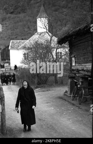 Loen 1947 poco più di 10 anni dopo il grande incidente di gara, la vita è tornata nei villaggi intorno a Loen. Il servizio è finito nella chiesa in legno di Loen, risalente a 100 anni fa. Vecchia donna vestita di nero sulla via di casa dopo il servizio. La chiesa sullo sfondo. Foto: TH. Scotaam / corrente / NTB Foto Stock