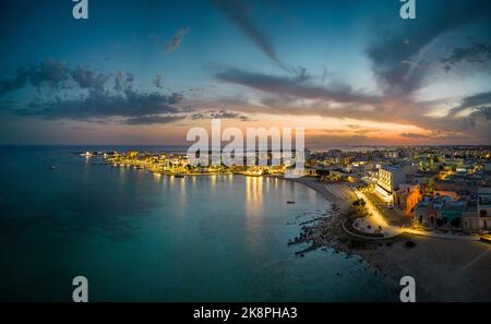 Una vista aerea del paesaggio marino illuminato di Porto Cesareo in Italia durante il tramonto Foto Stock