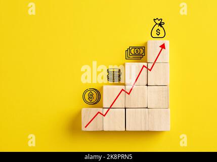 Aumento dei profitti, aumento degli utili, crescita finanziaria e crescita del risparmio o concetto di investimento. Carta crescente con icone di denaro su cubo di legno ladde Foto Stock