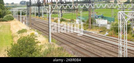 I cavi della trasmissione elettrica sospesa sopra una rotaia ferroviaria Foto Stock