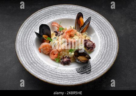 Riso bollito con gamberi, cozze, polpi e formaggio su un piatto Foto Stock