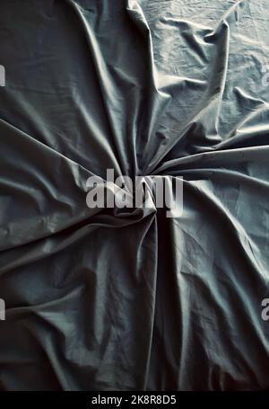 Un primo piano verticale di un tessuto verde stropicciato con una luce su di esso Foto Stock