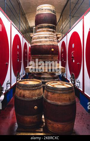 Botti di vino impilate in una colorata azienda vinicola italiana Foto Stock