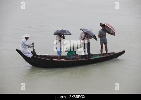 Dhaka, Bangladesh. 24th Ott 2022. I passeggeri del Bangladesh attraversano il fiume Buriganga mentre detengono ombrelli durante una forte pioggia e condizioni difficili causate dal ciclone Sitrang a Dhaka, Bangladesh, 24 ottobre 2022. Secondo la Bangladesh Inland Water Transport Authority (BIWTA) e il Dipartimento di Meteorologia del Bangladesh, il trasporto di acque interne è stato sospeso in quanto il ciclone Sitrang si avvicina dovrebbe attraversare la parte sud-sud-ovest del distretto di Barishal e Chattogram entro il 25 ottobre. Il Bangladesh Met Office ha avvertito che la tempesta ciclonica potrebbe intensificarsi ulteriormente e trasformarsi in un grave ciclone Foto Stock