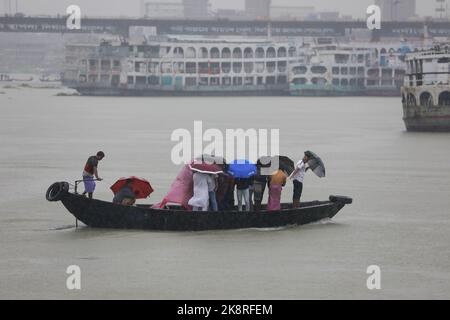 Dhaka, Bangladesh. 24th Ott 2022. I passeggeri del Bangladesh attraversano il fiume Buriganga mentre detengono ombrelli durante una forte pioggia e condizioni difficili causate dal ciclone Sitrang a Dhaka, Bangladesh, 24 ottobre 2022. Secondo la Bangladesh Inland Water Transport Authority (BIWTA) e il Dipartimento di Meteorologia del Bangladesh, il trasporto di acque interne è stato sospeso in quanto il ciclone Sitrang si avvicina dovrebbe attraversare la parte sud-sud-ovest del distretto di Barishal e Chattogram entro il 25 ottobre. Il Bangladesh Met Office ha avvertito che la tempesta ciclonica potrebbe intensificarsi ulteriormente e trasformarsi in un grave ciclone Foto Stock