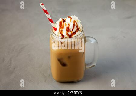 Latte cotte al caramello fatto in casa con panna montata in vaso di vetro, vista laterale. Foto Stock