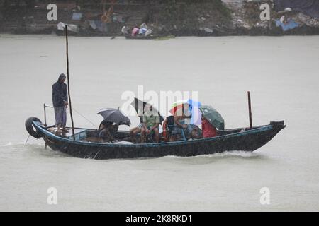 Dhaka, Bangladesh. 24th Ott 2022. I passeggeri del Bangladesh attraversano il fiume Buriganga mentre detengono ombrelli durante una forte pioggia e condizioni difficili causate dal ciclone Sitrang a Dhaka, Bangladesh, 24 ottobre 2022. Secondo la Bangladesh Inland Water Transport Authority (BIWTA) e il Dipartimento di Meteorologia del Bangladesh, il trasporto di acque interne è stato sospeso in quanto il ciclone Sitrang si avvicina dovrebbe attraversare la parte sud-sud-ovest del distretto di Barishal e Chattogram entro il 25 ottobre. Il Bangladesh Met Office ha avvertito che la tempesta ciclonica potrebbe intensificarsi ulteriormente e trasformarsi in un grave ciclone Foto Stock